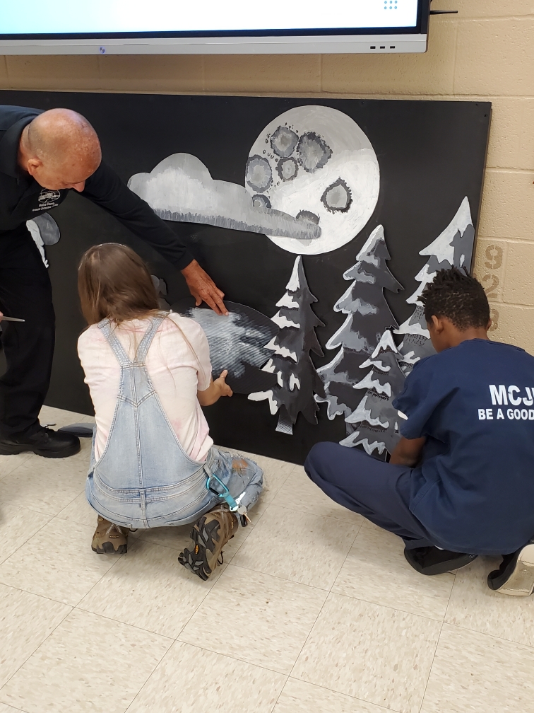 Two artists work with an inmate at the Medina County Juvenile Detention Center