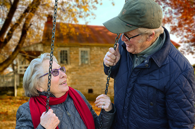 An aging woman on a swing looks up at her partner