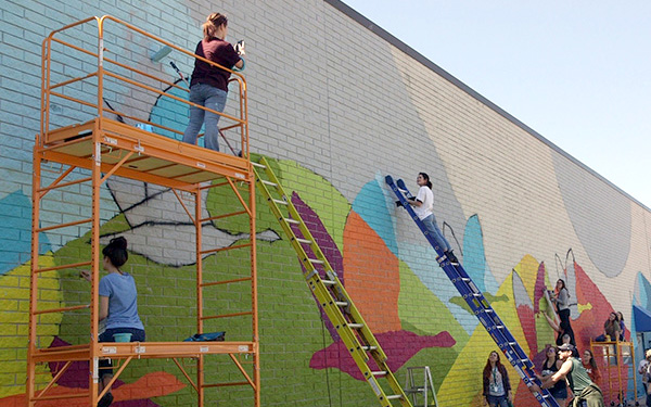 People on ladders painting a building