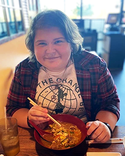 Blake Nicholas smiles while sitting at a table with a bowl of food