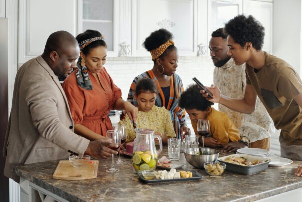 Black family gathers around kitchen