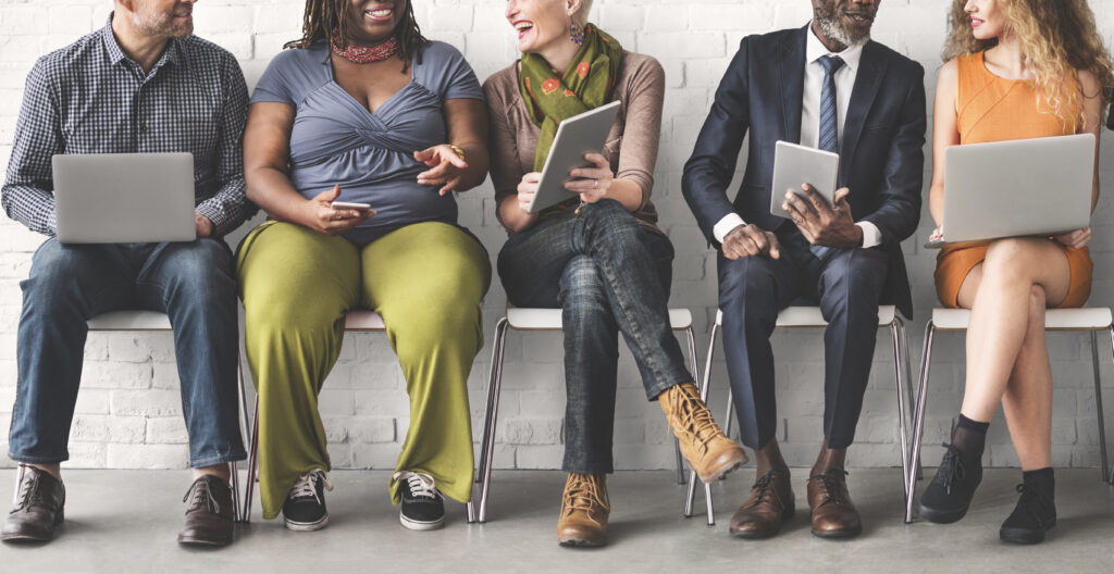 Professionals sitting in row of chairs with laptops and tablets