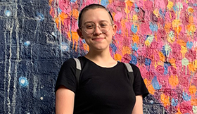 A GCEF scholarship recipient stands in front of a mural