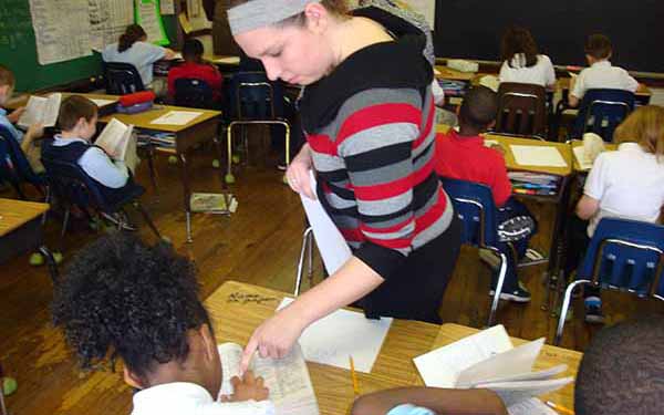 Woman points to dictionary on student's desk