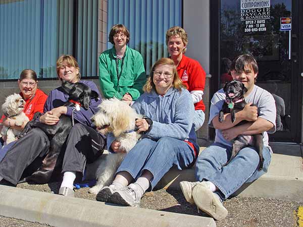 Employees at Hattie Larlham Doggie Day Care holding dogs