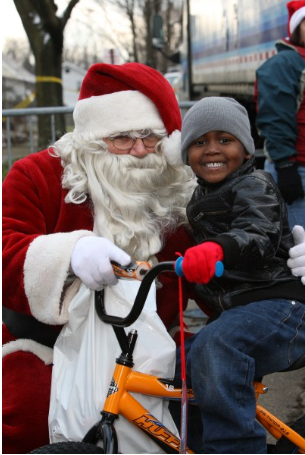 Santa poses for photo with child on bike