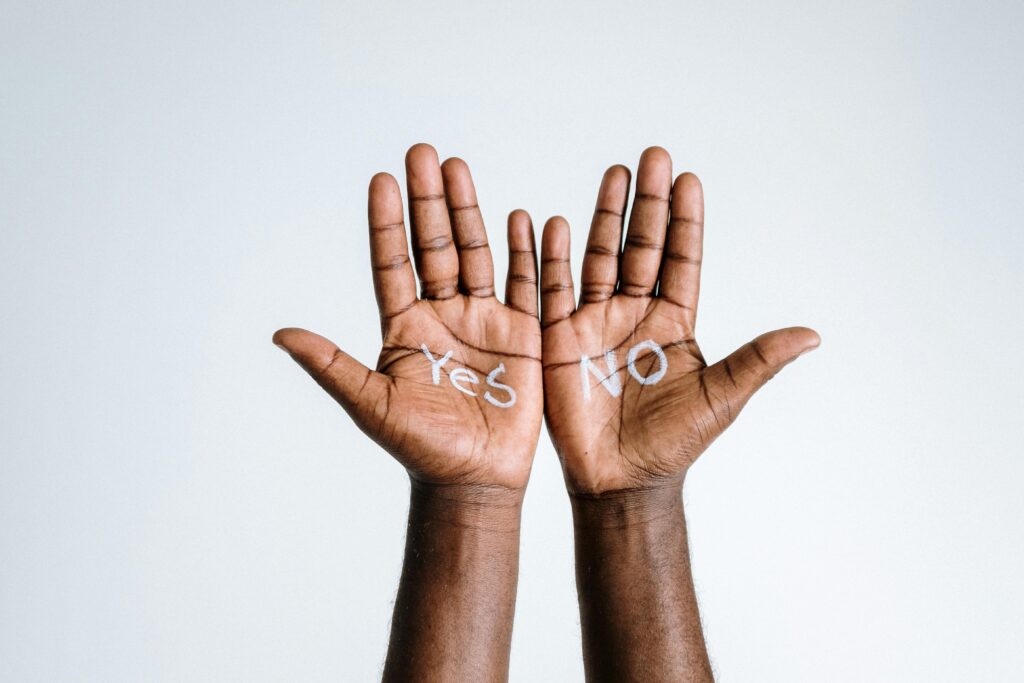 Two hands are opened with the word "yes" painted on the palm of the left one and "no" painted in the palm of the right hand. 