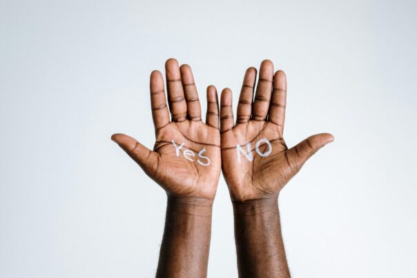 Two hands are opened with the word "yes" painted on the palm of the left one and "no" painted in the palm of the right hand.