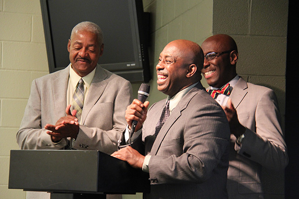 Three men smiling near a podium