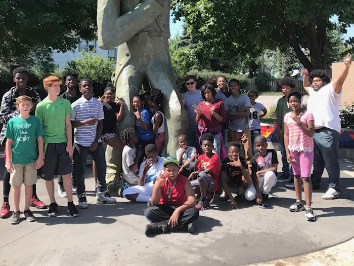 Group of kids standing around a statue