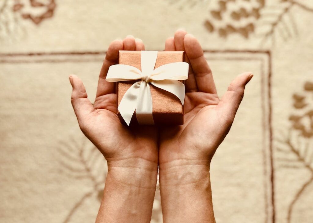 Hands holding gift box wrapped with a bow.