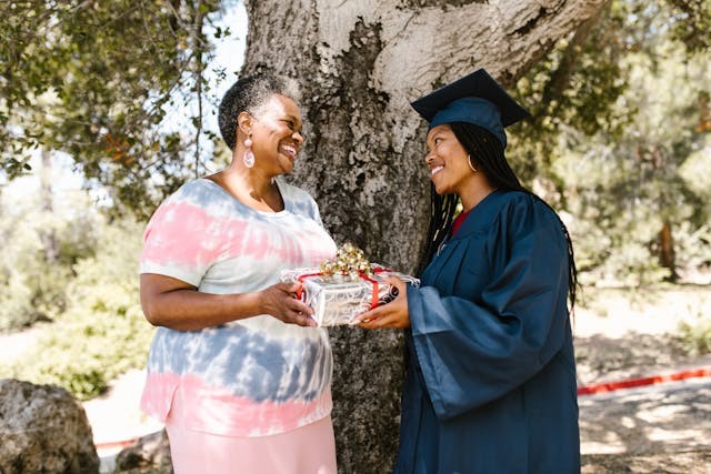 Grandmother gives gift to girl in graduation cap