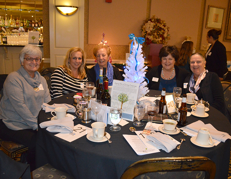 Women smile for photo at event table