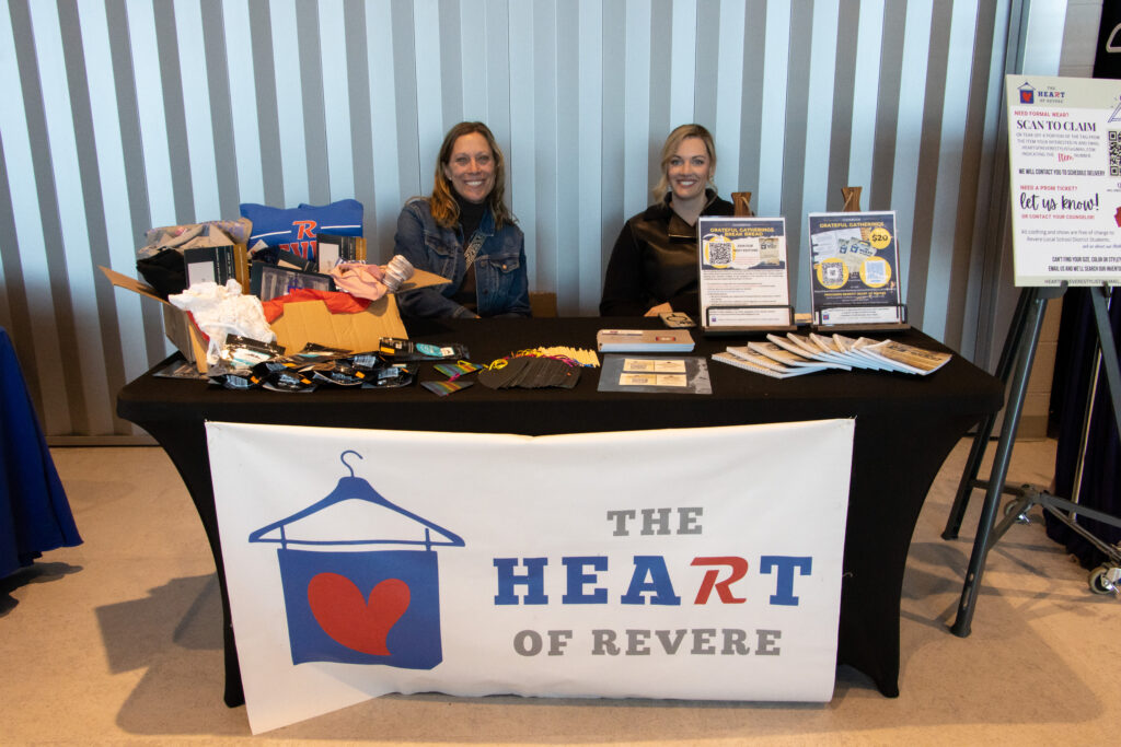 Two women sit at a table with a banner reading 'The Heart of Revere'