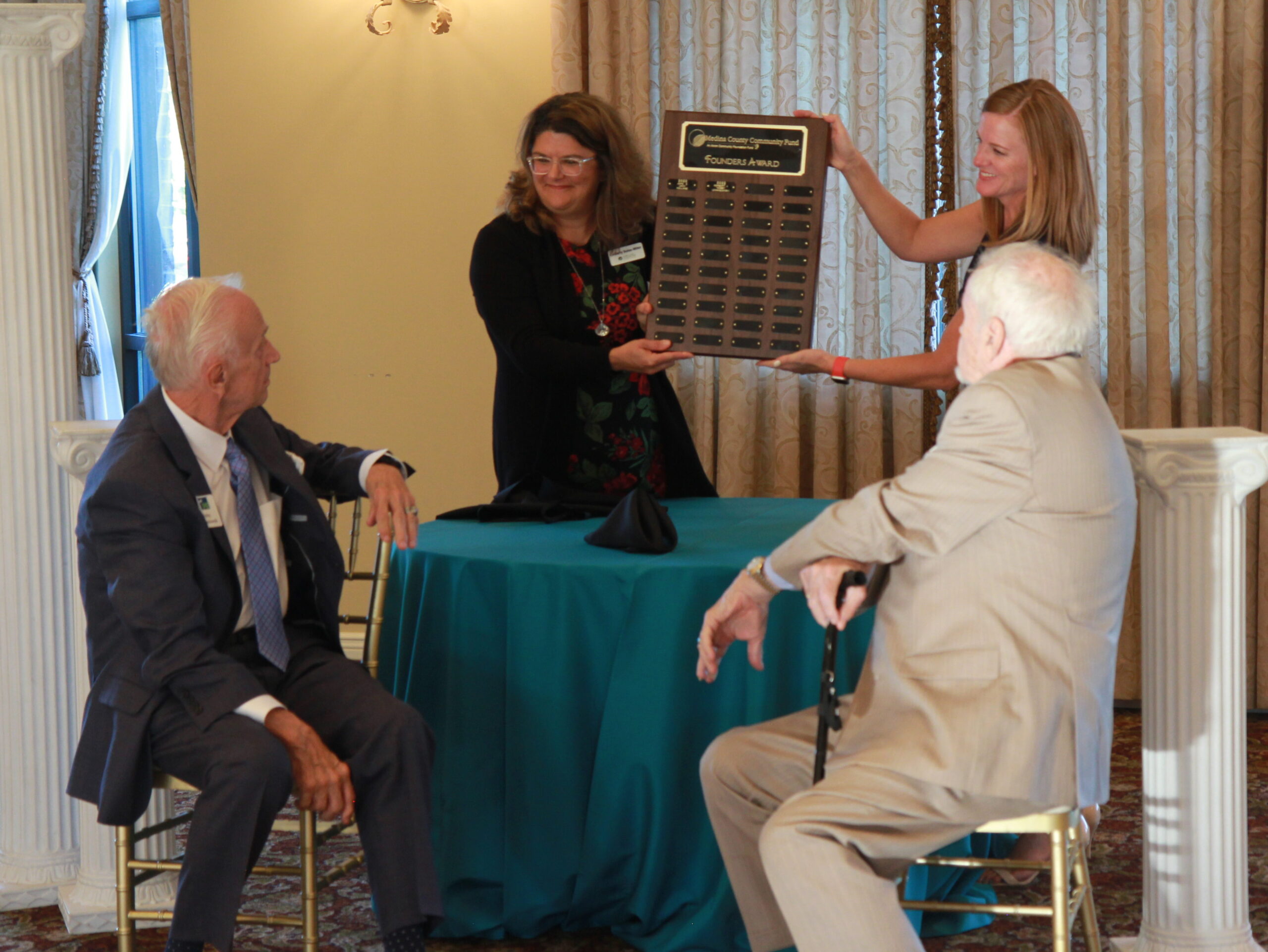 Kimberly Bolas Miller (left) and Erika Branch (right) present Norbert "Nobby" Lewandowski and Jack Holland with the first Medina County Community Fund Founders Award