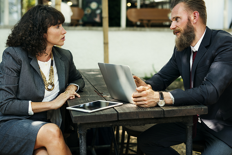 Man and woman in professional attire sitting at table