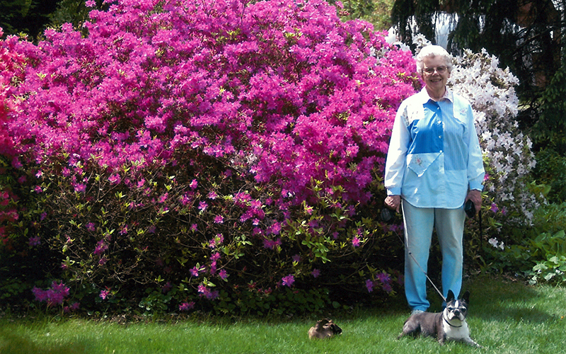 Woman stands in front of large flower bush