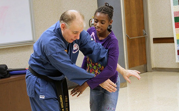 Martial arts instructor demonstrates maneuver with teen girl
