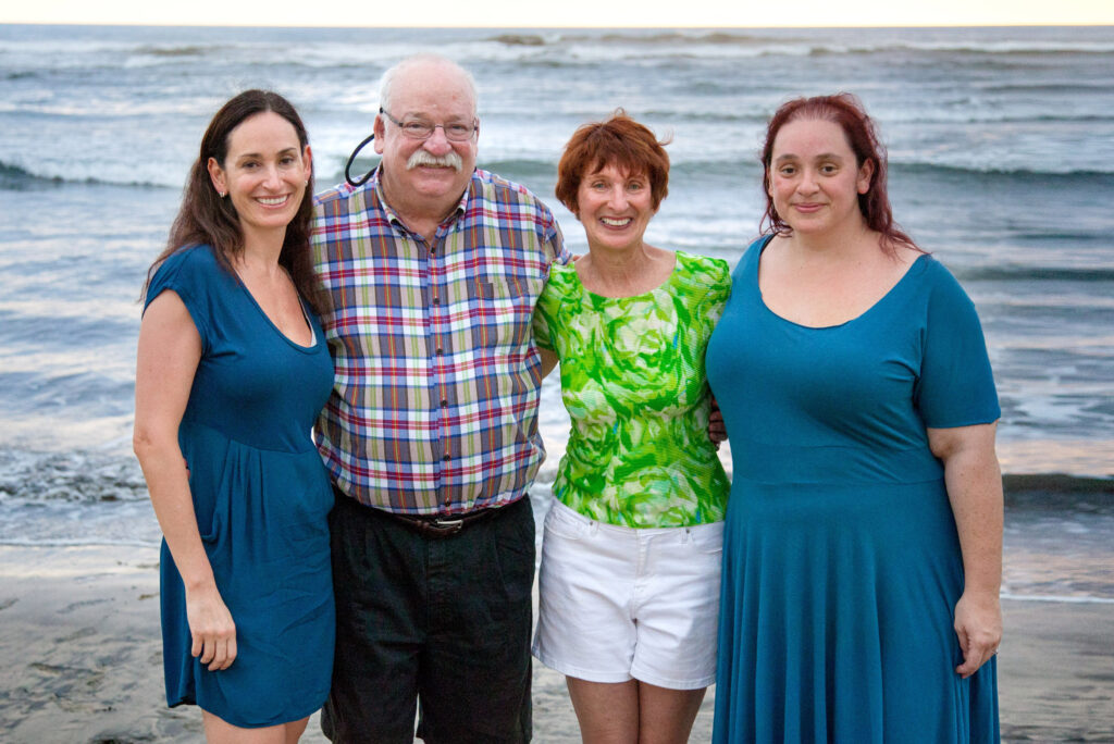 Four people smiling in front of the ocean