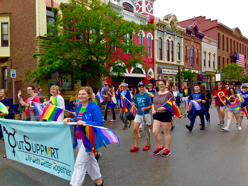 People walk in parade with rainbow flags