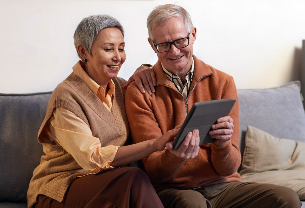 Man and woman smiling while using a tablet