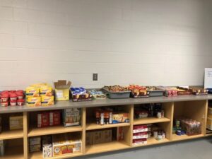 Non-perishable food items are organized on a countertop with two shelves underneath.