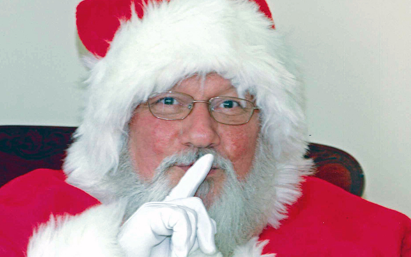 Santa holding one finger up to his lips
