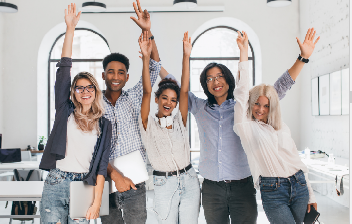 Five college students smiling with hands in the air