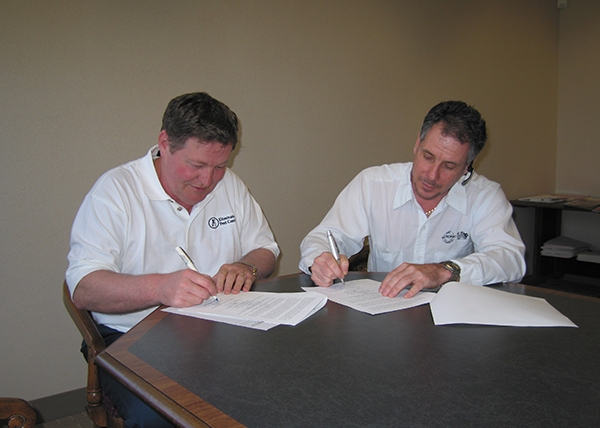 Two men sitting at a table signing documents