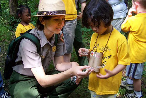 Park ranger kneeling down next to child