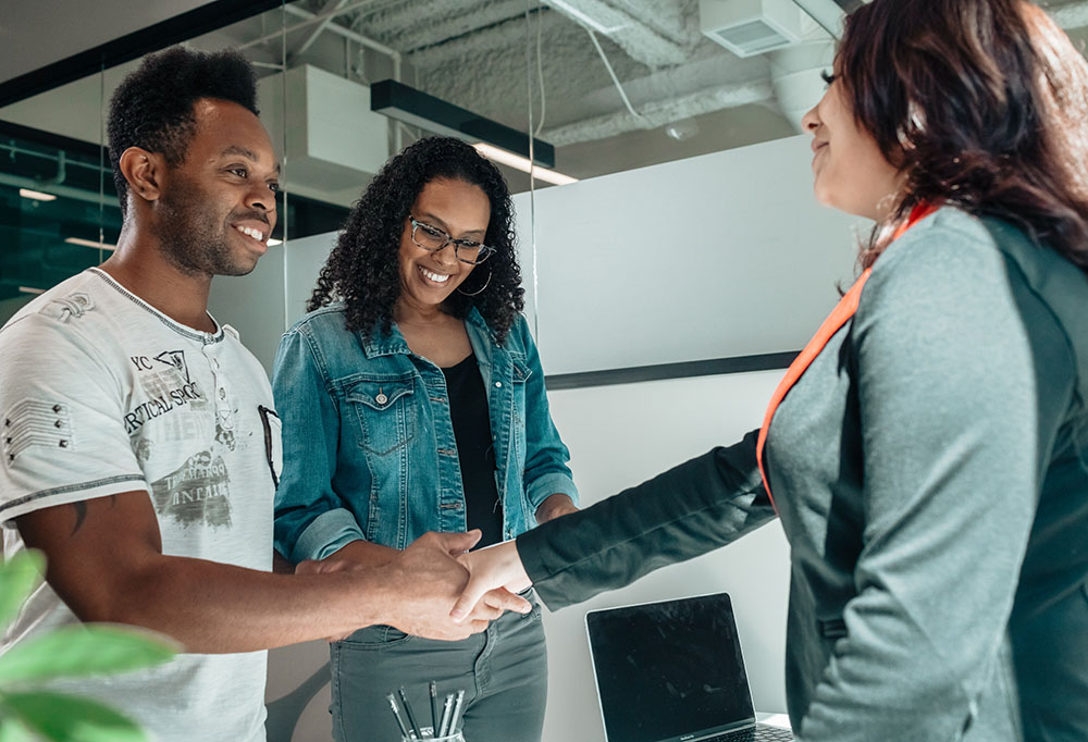 Advisor shaking hands with two smiling clients