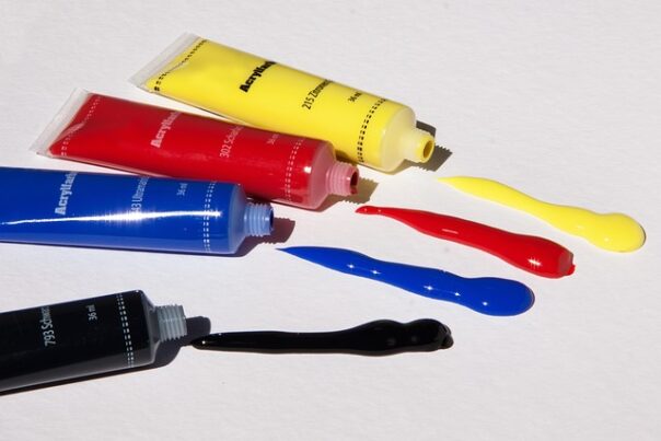 open tubes of yellow, red, blue and black paint, with some paint spilled out near the openings