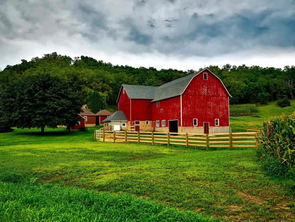 A red barn surrounded by trees and farmland