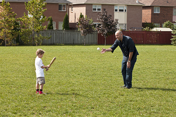 Father and son playing baseball in yard