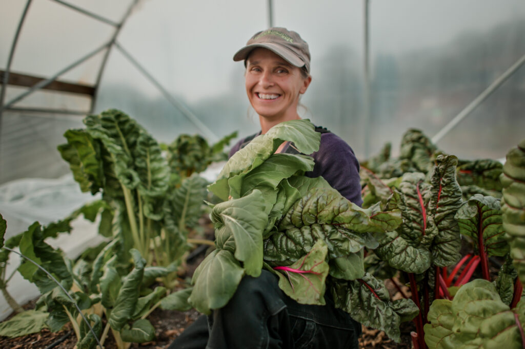 Lisa Nunn, executive director of Let's Grow Akron, poses among green leaves of freshly grown food. 