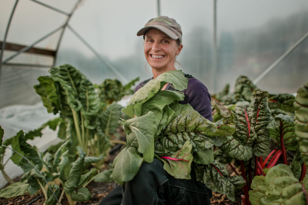 Lisa Nunn, executive director of Let's Grow Akron, poses among green leaves of freshly grown food.