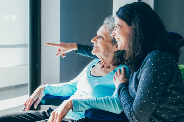 Older mother and daughter smiling and looking out a window