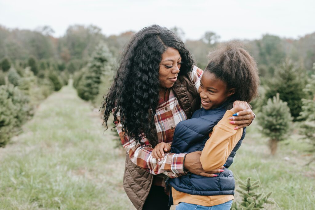 Mother hugging daughter at a tree farm.