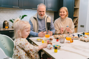 Grandparents paint eggs with young girl