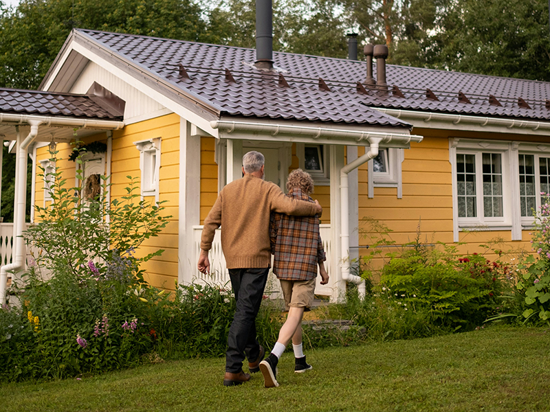 grandfather and grandson walking toward a yellow house