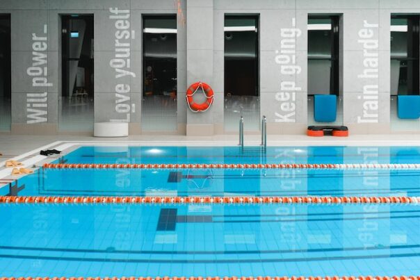 An empty swimming pool with different lanes in the pool marked by orange rope, and inspirational messages are superimposed on the wall.
