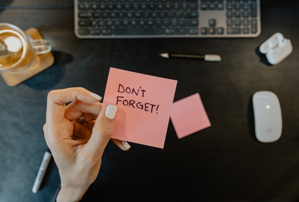 Person holding note that says "Don't Forget"