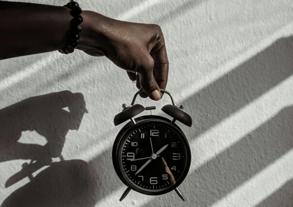 A hand is holding a traditional alarm clock